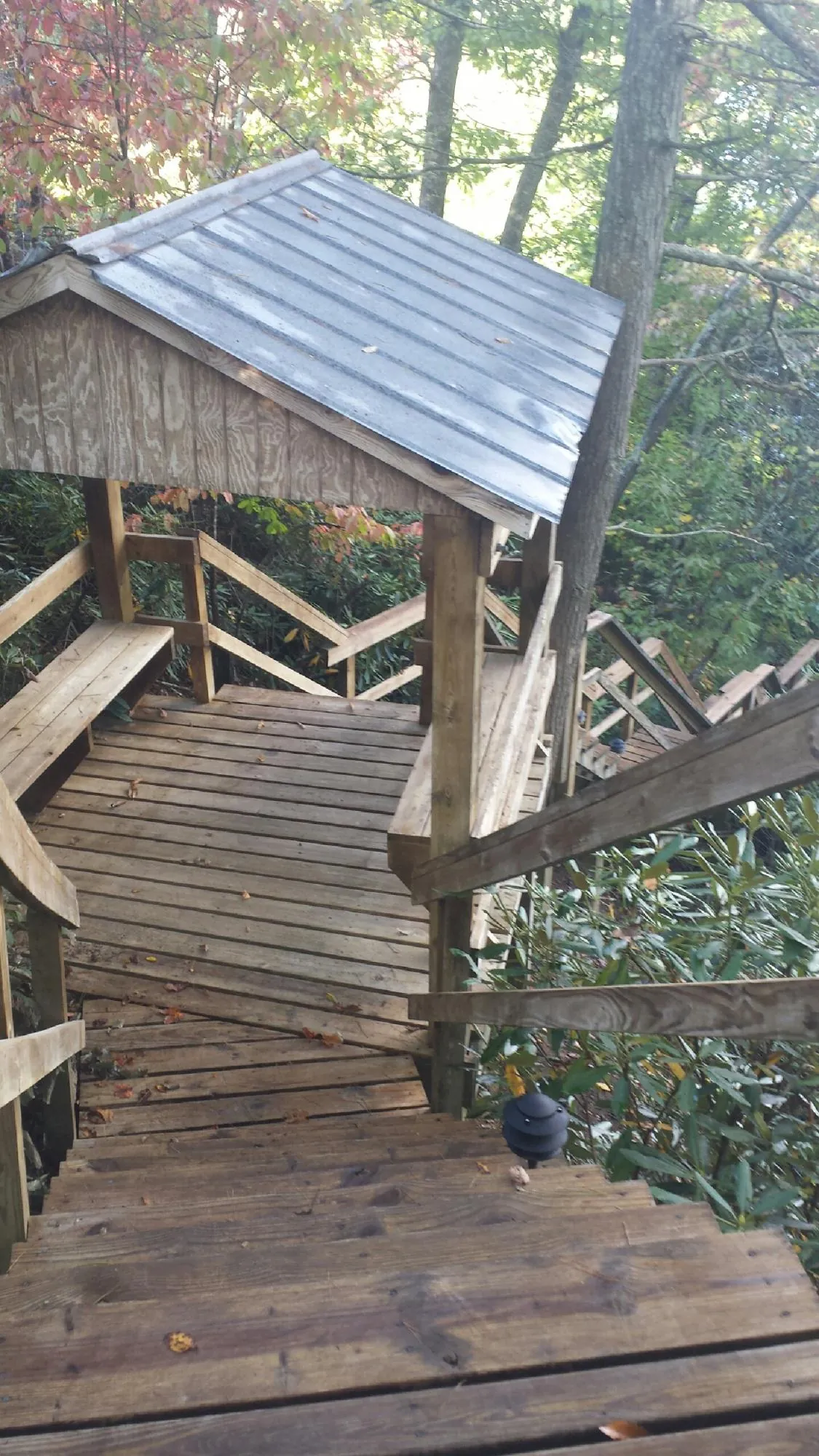 Metal roofed shelter over wooden steps on a wooded walkway — Skylight Repair & Installation work by our crew in Houston