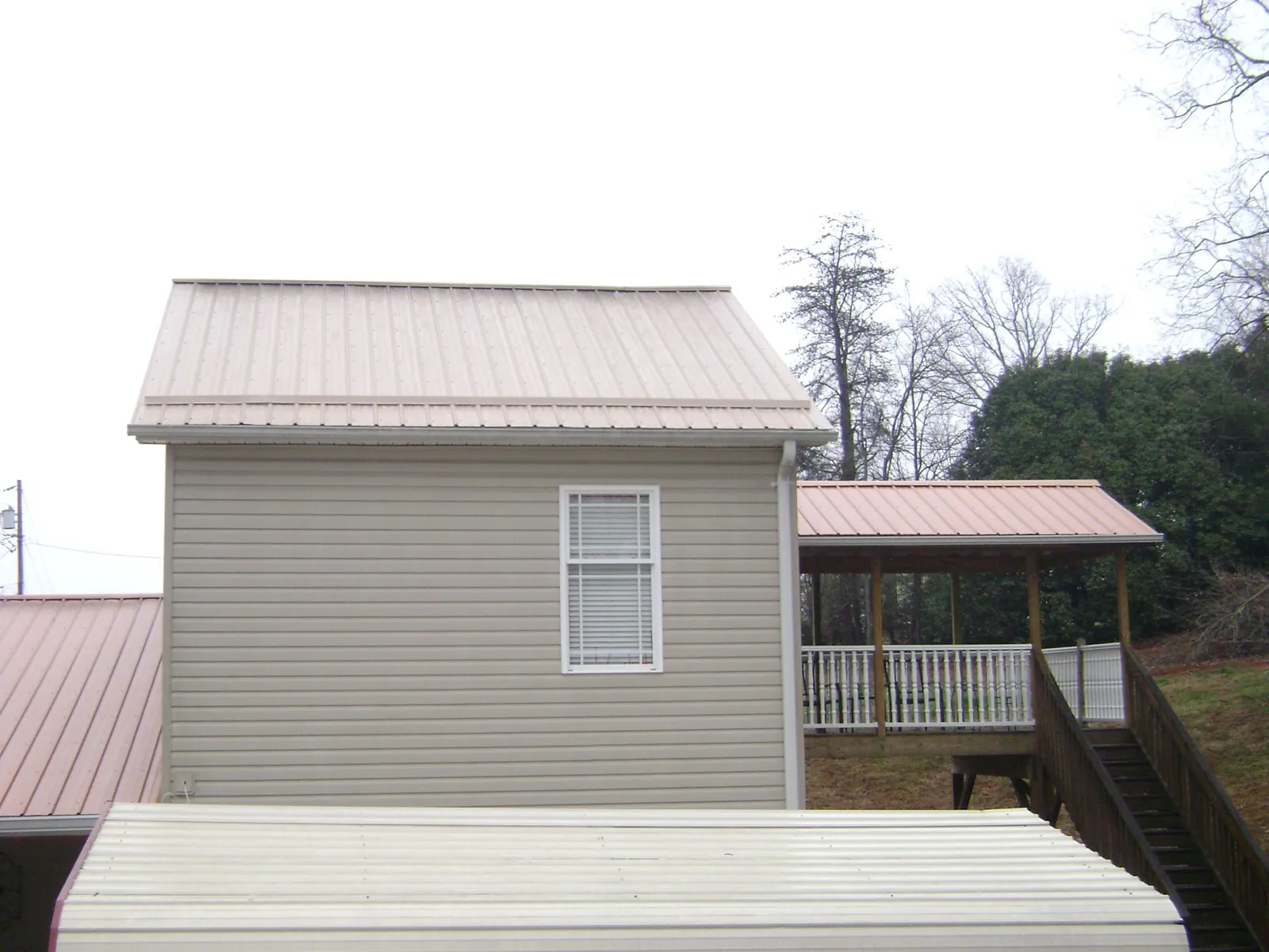 Tan metal roofs on a two story addition and attached porch, from a Roof Replacement job in Houston